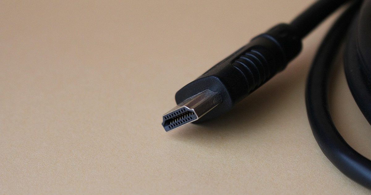 a black HDMI cable connector with gold pins on a tan surface