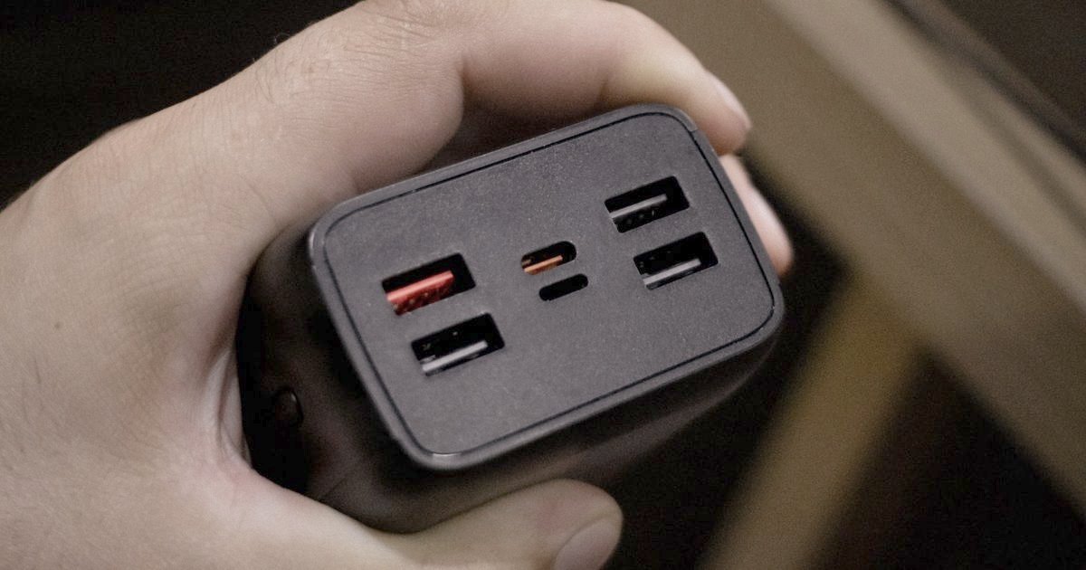 A large black power bank held in one hand, ports facing out