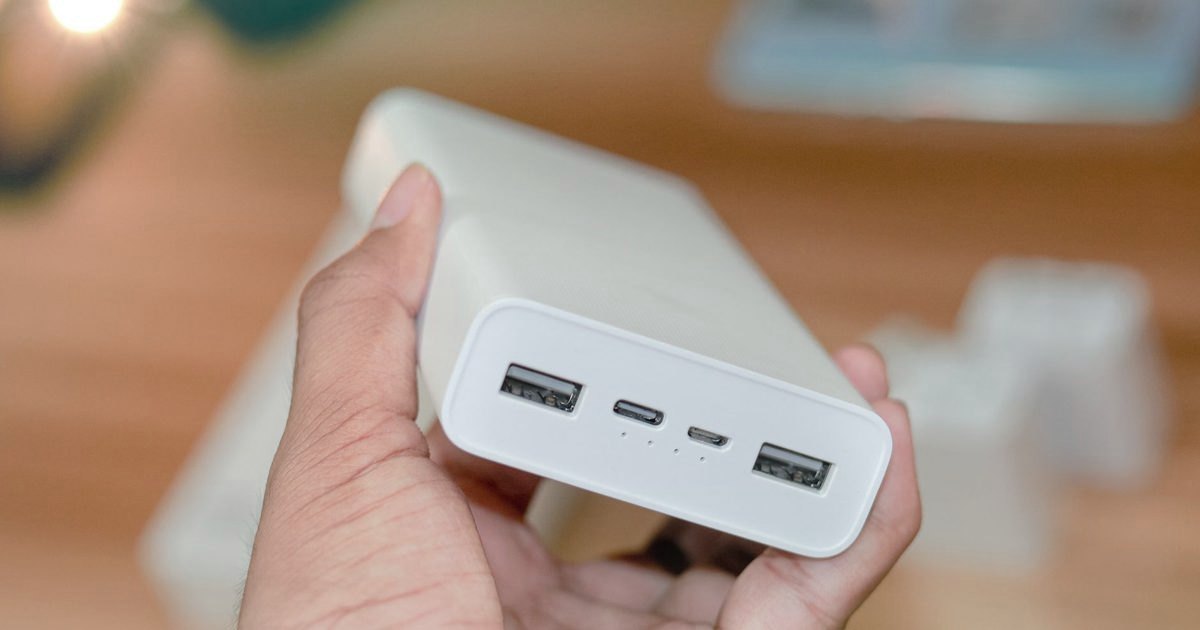 A white power bank held in one hand, USB-A and USB-C ports visible