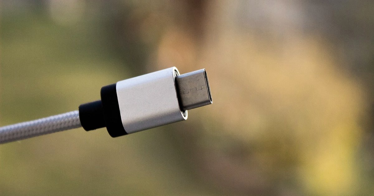 Silver USB-C plug on a braided grey cable against a warm blurred background