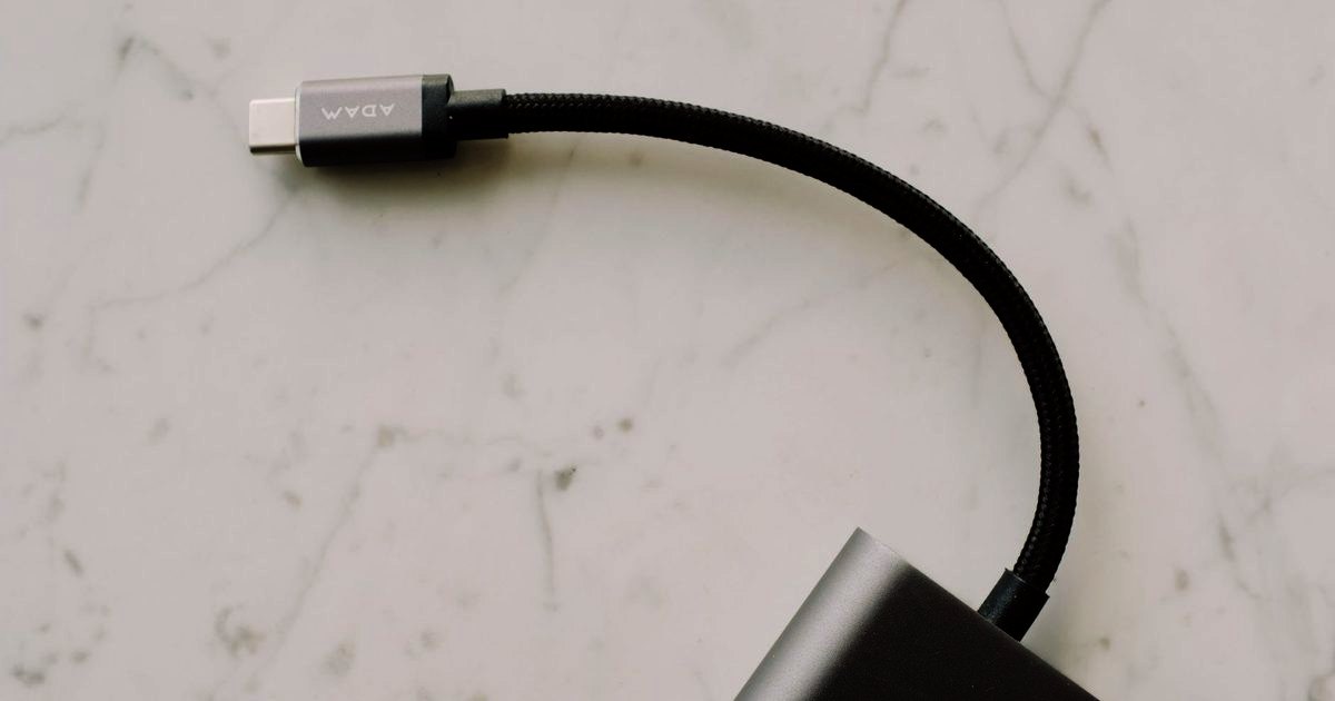 A braided black USB-C cable coiled on a marble surface