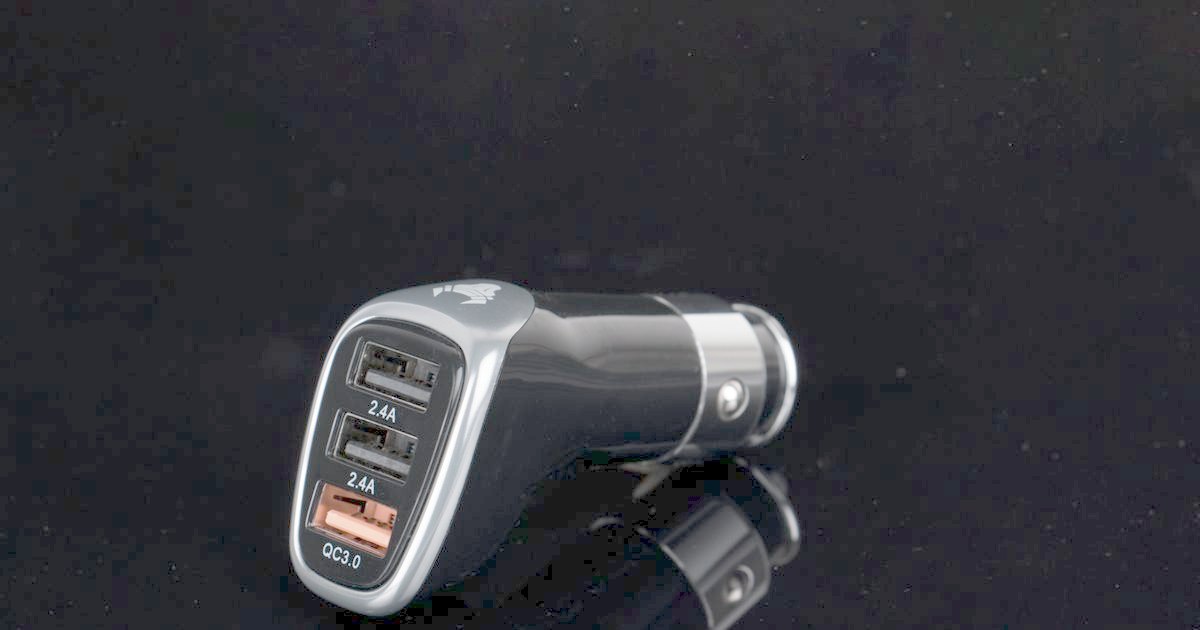 A black car charger with three USB ports on a dark background