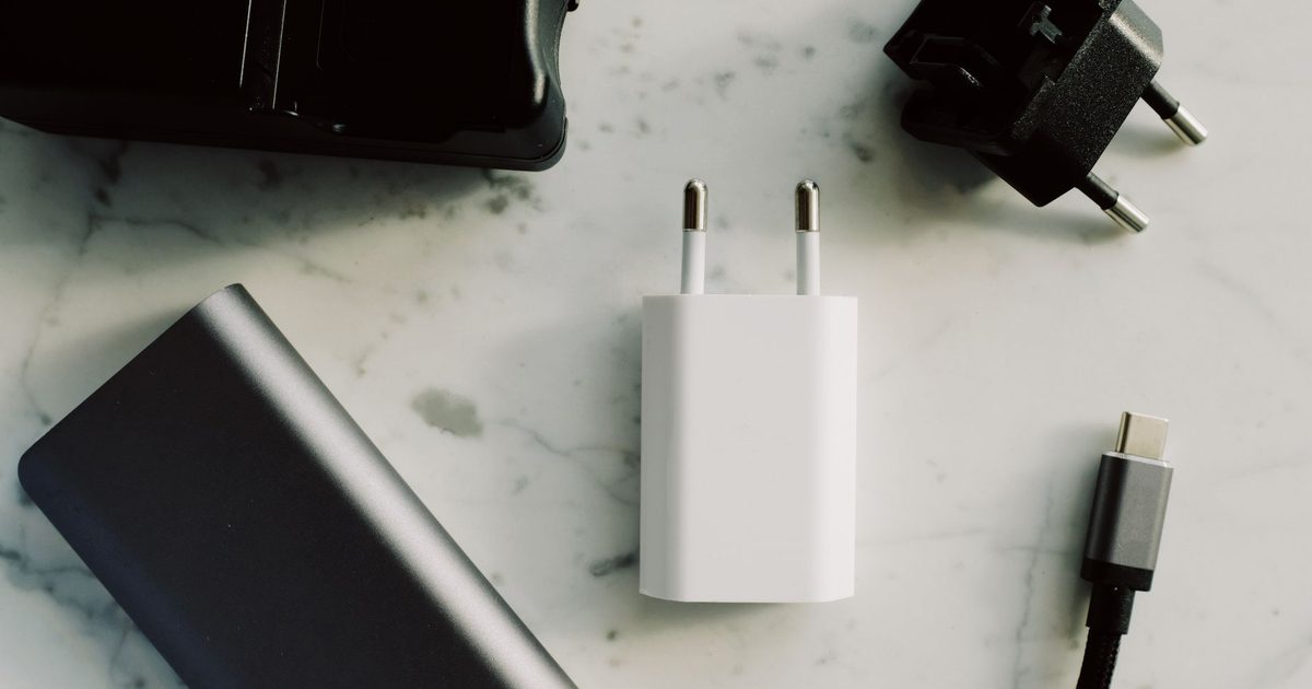 a white usb wall charger on marble beside a cable and power bank
