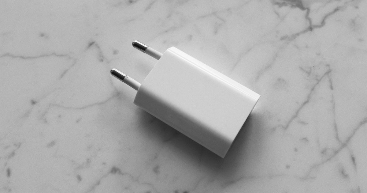 a small white usb wall charger with two pins on marble