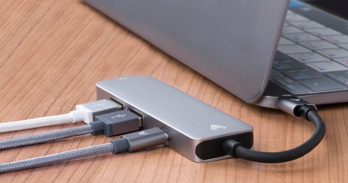 A USB-C dock with several cables plugged in beside a laptop