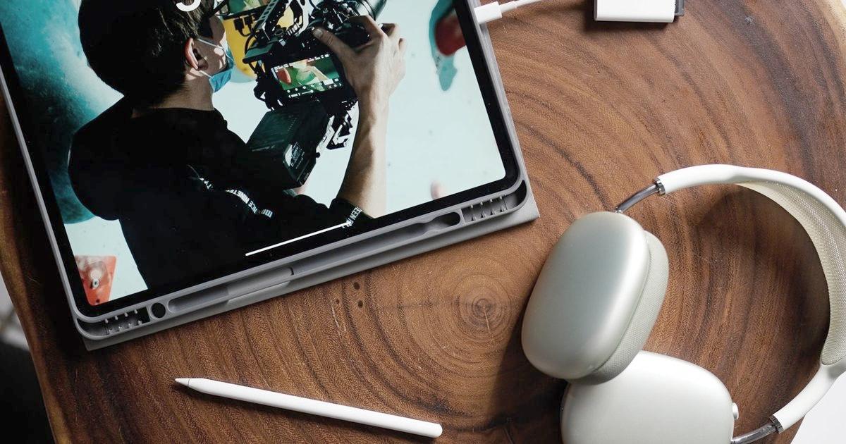 iPad in a grey case on a wooden table with a pencil and headphones