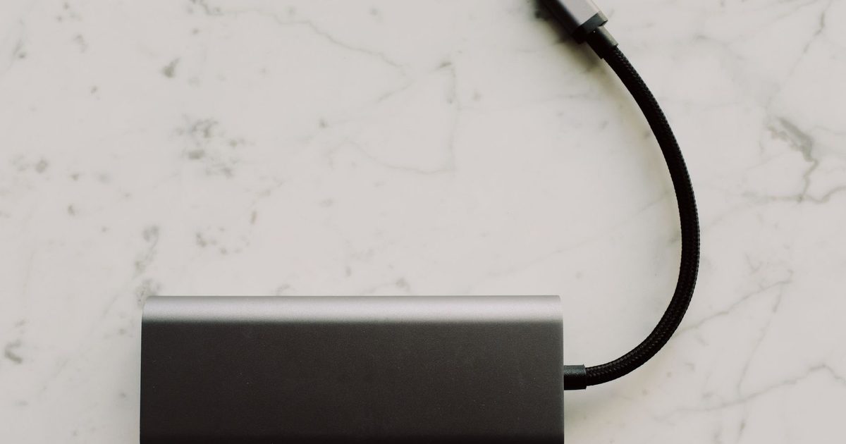 A grey USB-C hub with a braided cable, seen from above on marble