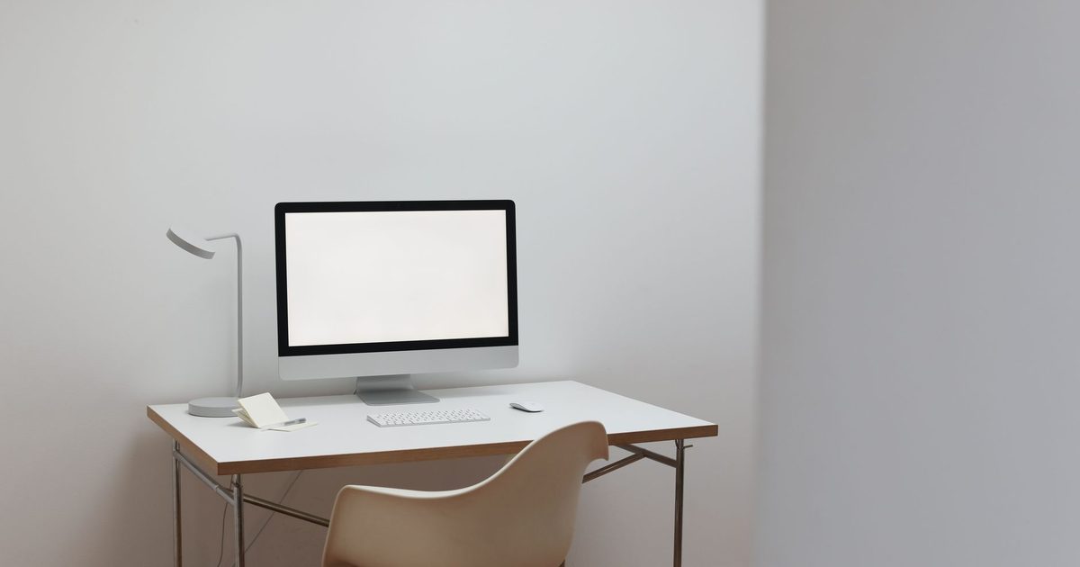 a monitor with a blank screen on a minimalist white desk with a keyboard