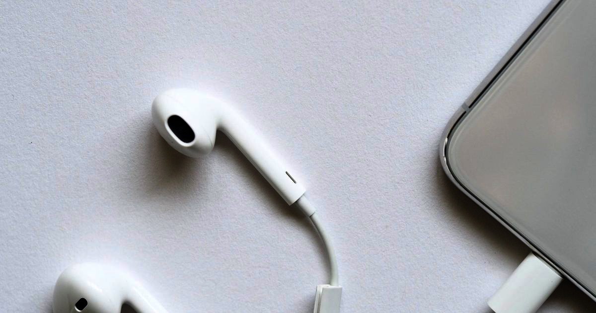 White wired earphones and a small adapter at the edge of a phone