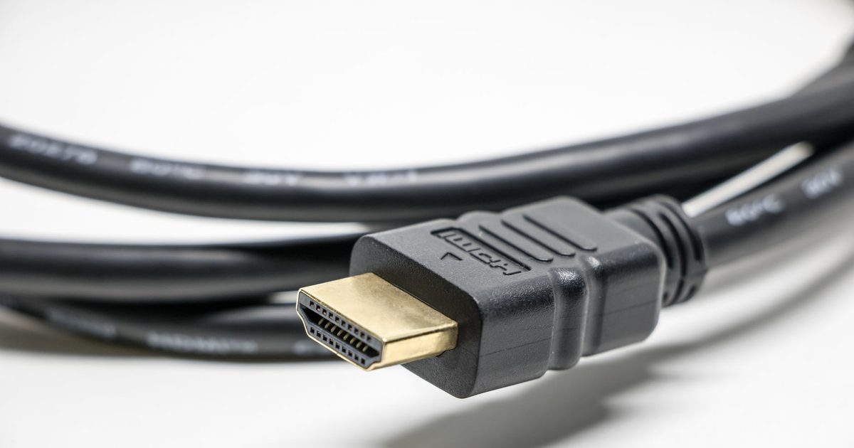 Coiled black HDMI cable with a gold-plated plug on a white surface
