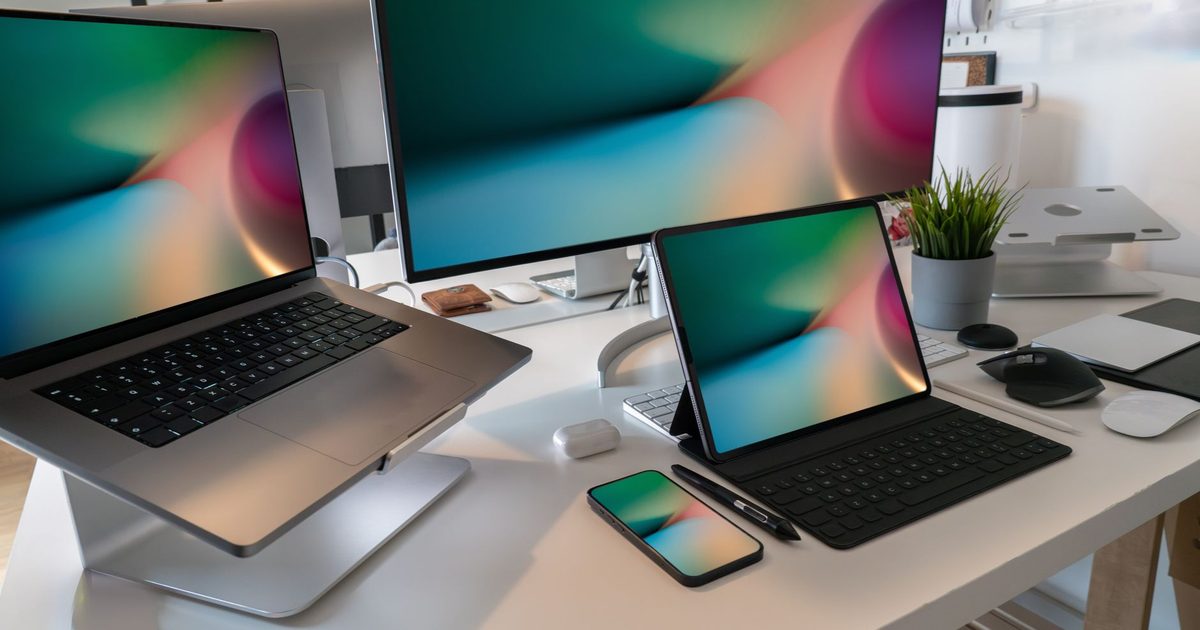 a tablet in a keyboard case beside a large monitor showing the same wallpaper
