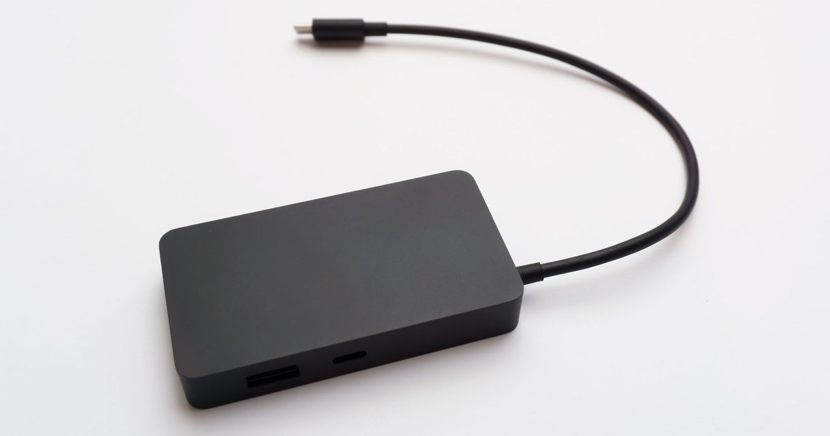 a small black usb hub with a usb-c cable on a white background