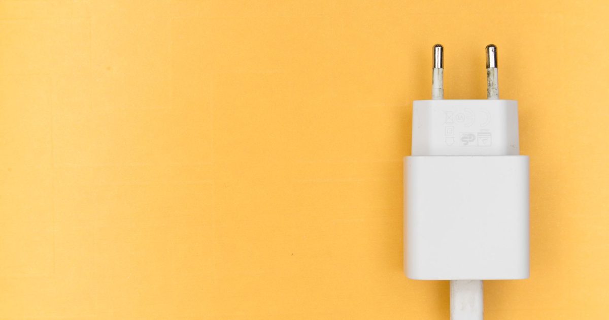 a white usb charger plug with its cable on a yellow background
