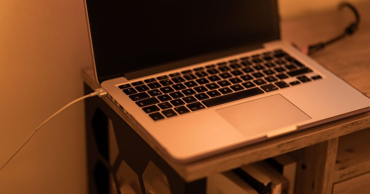 a laptop on a desk with a charging cable plugged into its side