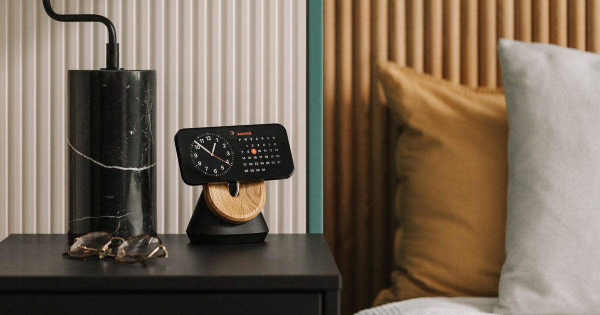 A phone in clock mode on a magnetic bedside charging stand